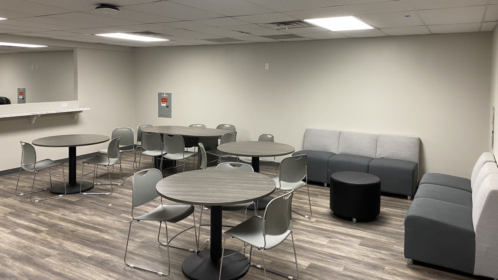 Modern office break room with round tables, chairs, and a couch. 