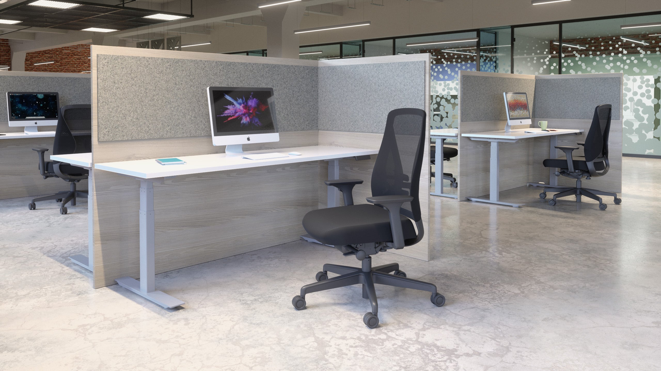 Modern office setup with desks, chairs, and computer monitors in a well-lit room.