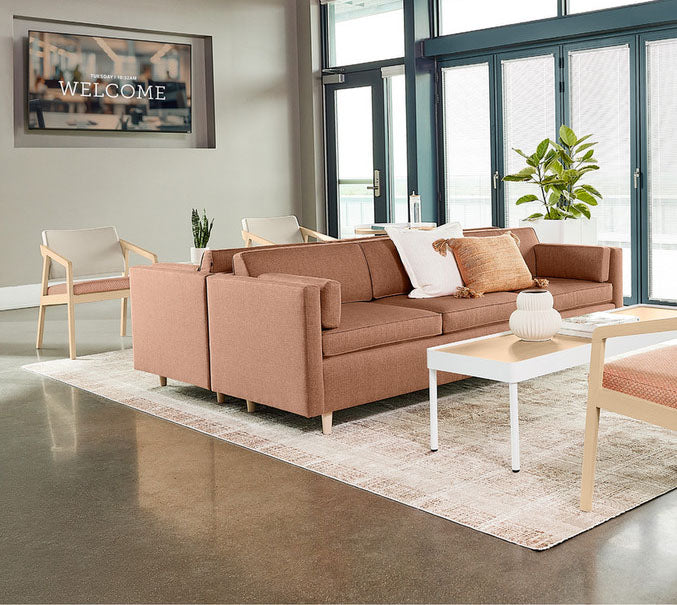 Brown sectional sofa in a modern living room with a 'Welcome' sign on the wall.